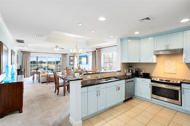 kitchen with kitchen peninsula, appliances with stainless steel finishes, ceiling fan with notable chandelier, light colored carpet, and sink