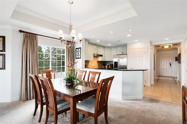 dining room featuring light carpet, a raised ceiling, ornamental molding, and a notable chandelier