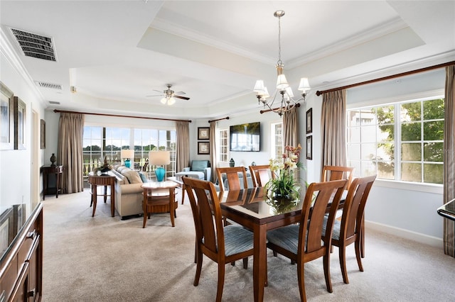 dining area featuring ceiling fan with notable chandelier, a raised ceiling, light colored carpet, and ornamental molding