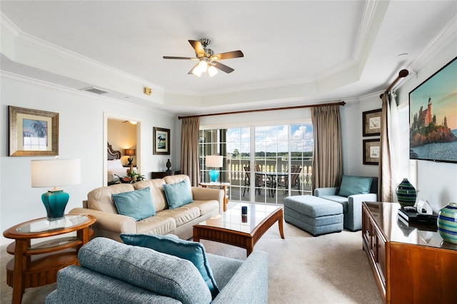 carpeted living room with a raised ceiling, ceiling fan, and ornamental molding