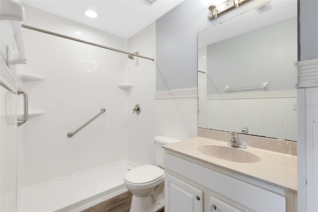 bathroom with tiled shower, vanity, wood-type flooring, and toilet