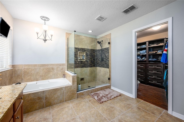 bathroom featuring independent shower and bath, tile patterned flooring, vanity, a notable chandelier, and a textured ceiling