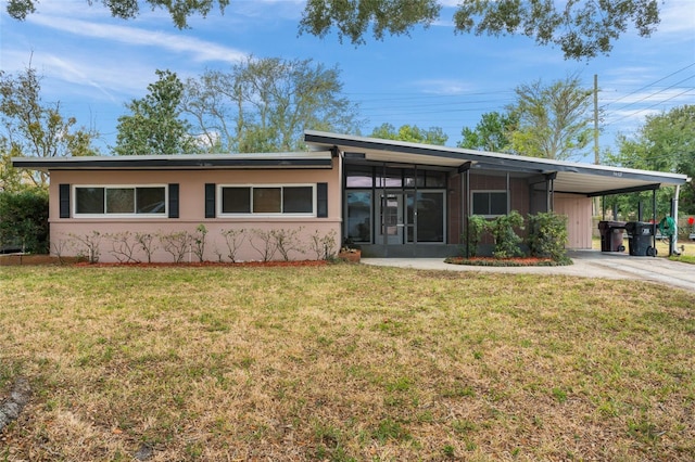 view of front of property featuring a front lawn, a carport, and a sunroom