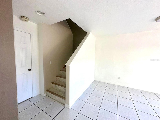 stairs featuring tile patterned flooring and a textured ceiling