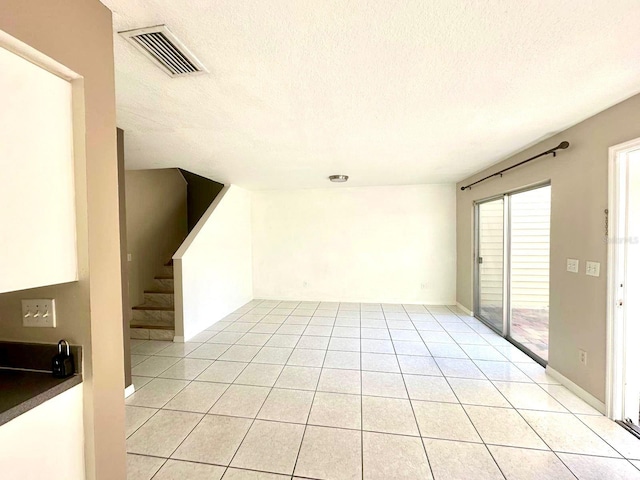 tiled spare room featuring a textured ceiling