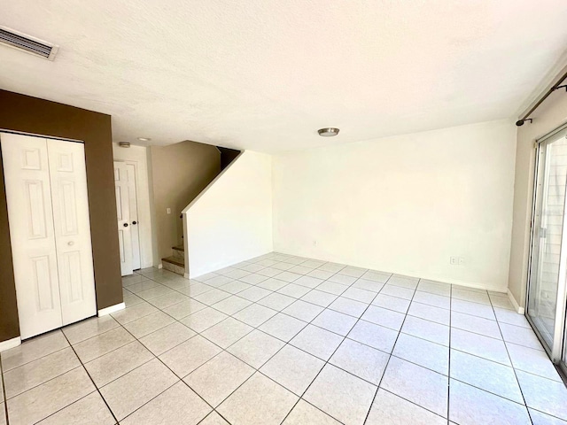 tiled empty room with a textured ceiling