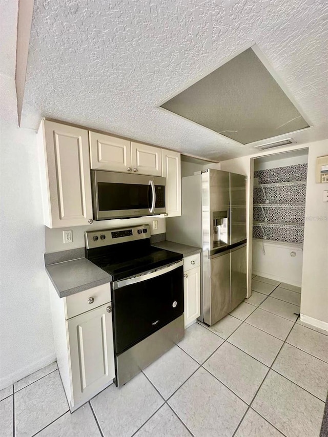 kitchen featuring a textured ceiling, light tile patterned flooring, and stainless steel appliances