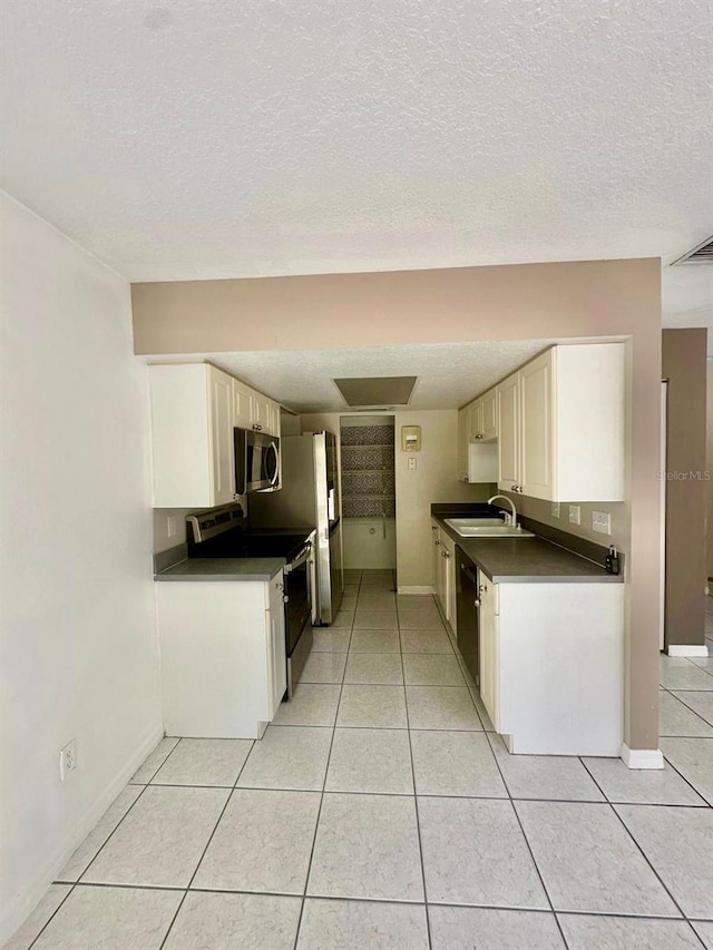 kitchen featuring white cabinets, sink, light tile patterned floors, a textured ceiling, and appliances with stainless steel finishes