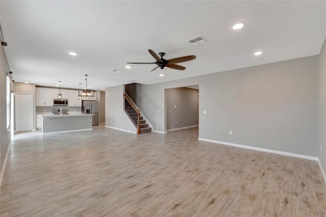 unfurnished living room with ceiling fan, sink, and light hardwood / wood-style floors