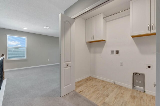 clothes washing area with cabinets, hookup for a gas dryer, washer hookup, a textured ceiling, and light colored carpet