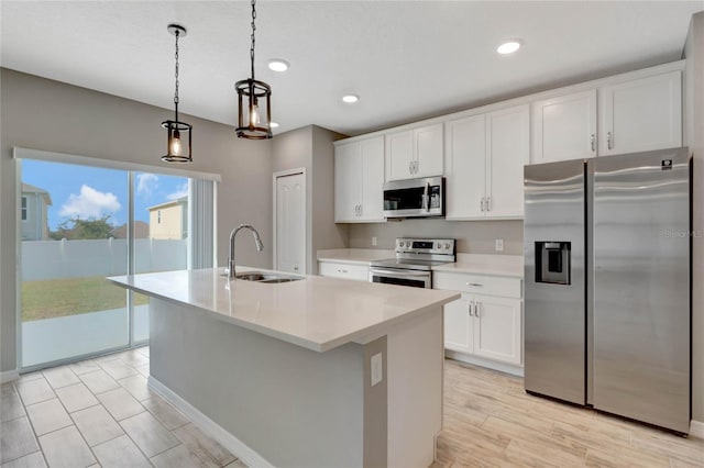 kitchen featuring sink, stainless steel appliances, white cabinetry, and an island with sink