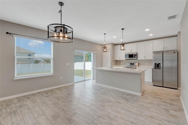 kitchen with white cabinetry, hanging light fixtures, stainless steel appliances, a chandelier, and a kitchen island with sink