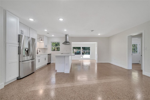 kitchen with white cabinets, sink, wall chimney exhaust hood, a kitchen island, and stainless steel appliances