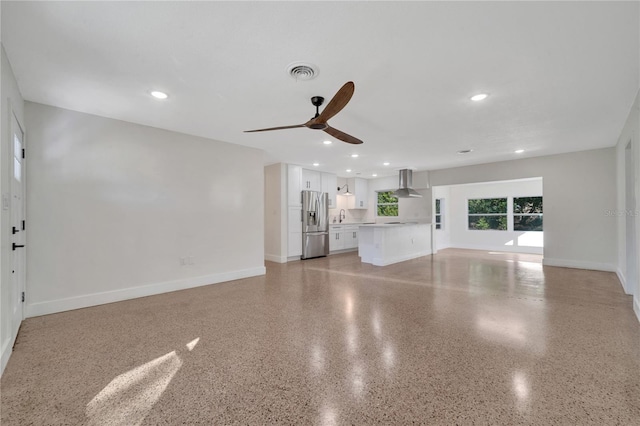 unfurnished living room featuring ceiling fan and sink