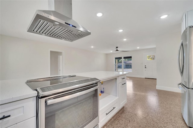 kitchen with stainless steel appliances, white cabinetry, ceiling fan, and wall chimney range hood