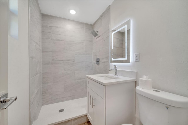 bathroom with vanity, toilet, and a tile shower