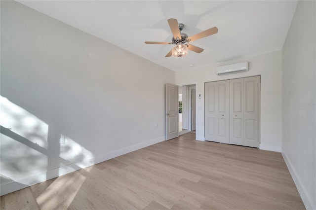 unfurnished bedroom featuring ceiling fan, a closet, light hardwood / wood-style floors, and a wall mounted air conditioner