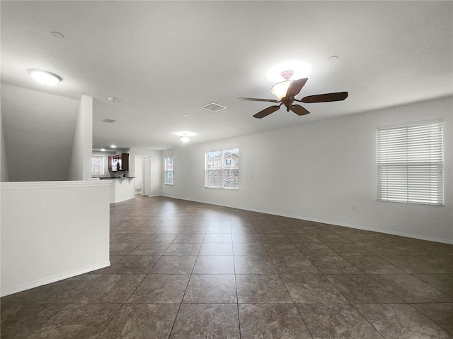 empty room with dark tile patterned flooring and ceiling fan