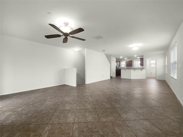 unfurnished living room featuring dark tile patterned floors and ceiling fan