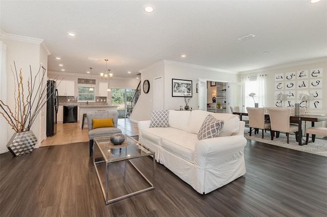 living room with hardwood / wood-style floors, crown molding, and an inviting chandelier