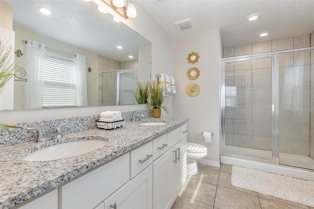 bathroom featuring tile patterned floors, a textured ceiling, toilet, vanity, and a shower with shower door