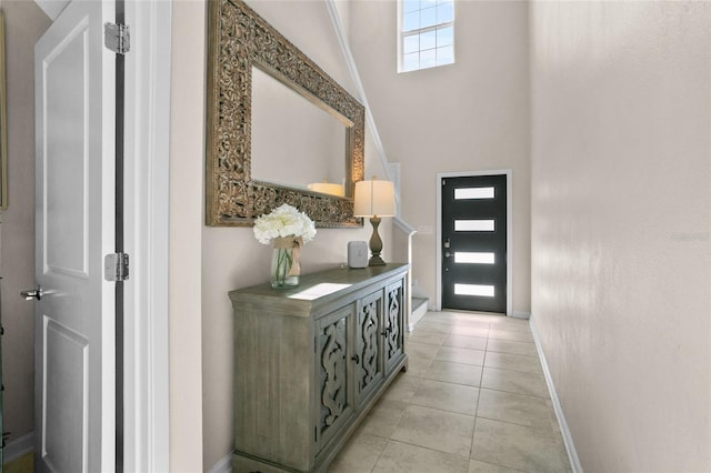 foyer featuring a healthy amount of sunlight, light tile patterned flooring, and vaulted ceiling