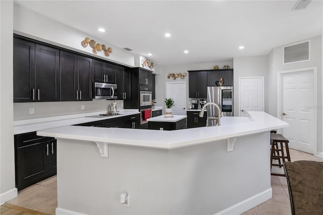 kitchen with a large island, light tile patterned flooring, a breakfast bar area, and appliances with stainless steel finishes