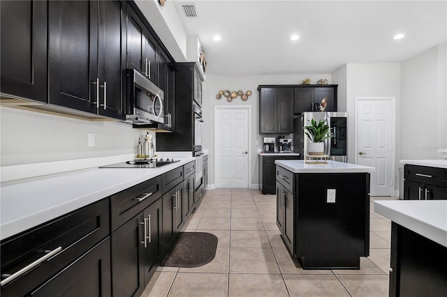 kitchen with appliances with stainless steel finishes, light tile patterned floors, and a kitchen island