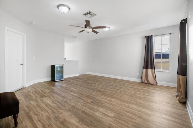 empty room with ceiling fan, light hardwood / wood-style floors, and wine cooler