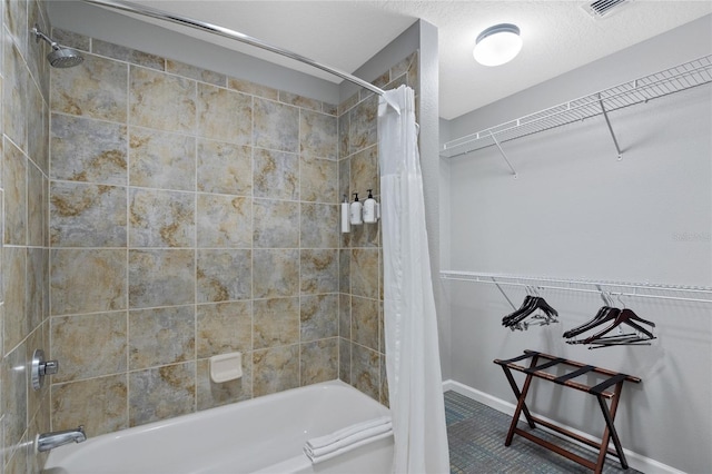 bathroom featuring shower / bath combination with curtain, baseboards, visible vents, and a textured ceiling