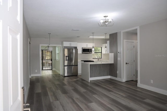 kitchen featuring pendant lighting, white cabinets, dark hardwood / wood-style floors, kitchen peninsula, and stainless steel appliances