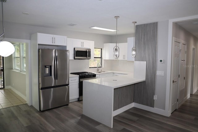 kitchen featuring appliances with stainless steel finishes, dark hardwood / wood-style floors, white cabinetry, and hanging light fixtures