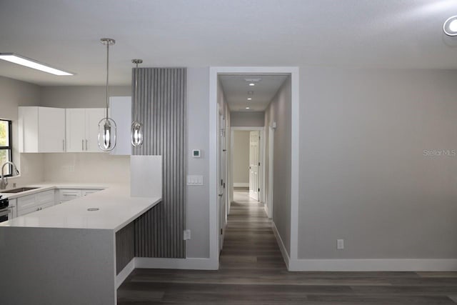 kitchen featuring white cabinets, sink, dark hardwood / wood-style floors, decorative light fixtures, and kitchen peninsula