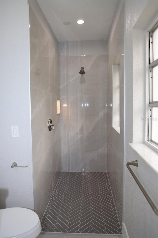 bathroom featuring a tile shower and toilet