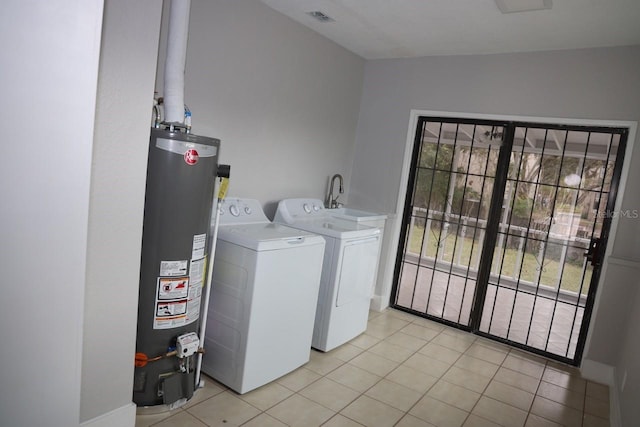 washroom with washer and clothes dryer, light tile patterned floors, and water heater