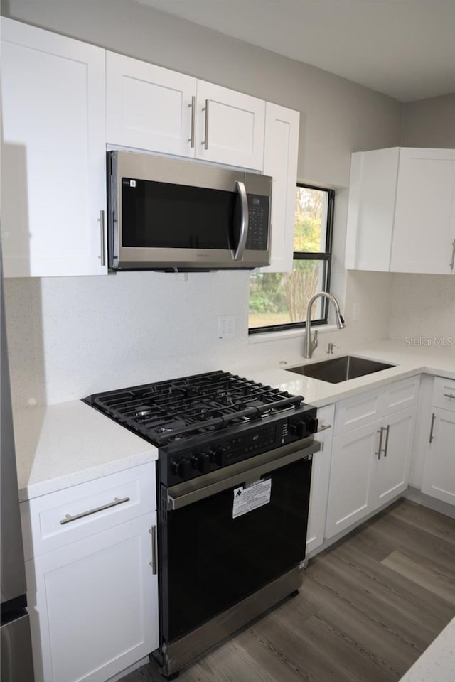 kitchen with white cabinets, dark hardwood / wood-style flooring, sink, and appliances with stainless steel finishes