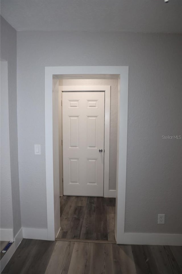 corridor with dark hardwood / wood-style flooring