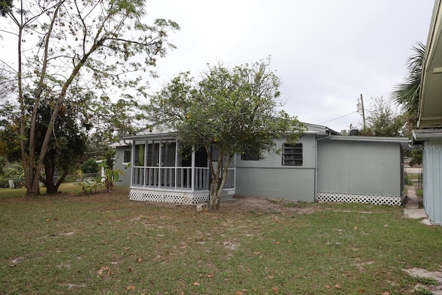 back of property featuring a sunroom and a lawn