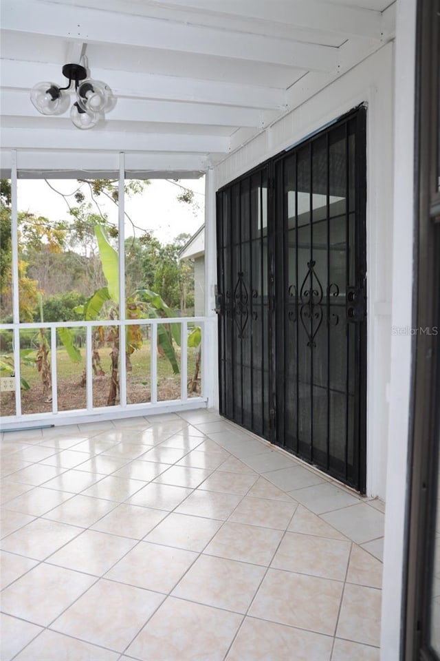 unfurnished sunroom with beamed ceiling, a wealth of natural light, and a notable chandelier