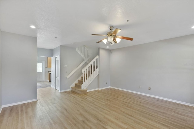 unfurnished room with ceiling fan, a textured ceiling, and light wood-type flooring