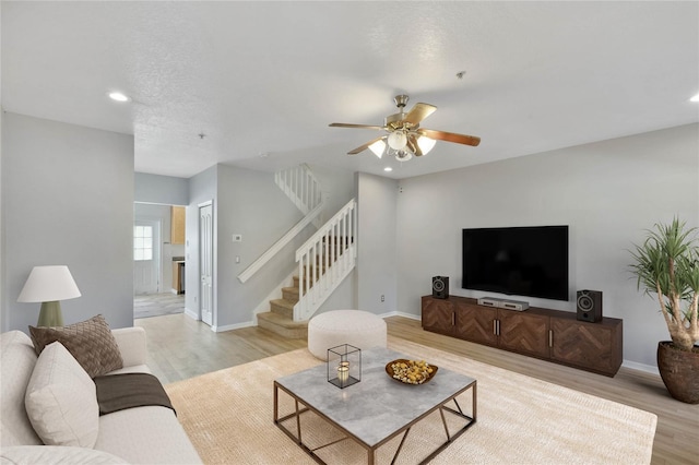 living room featuring ceiling fan, a textured ceiling, and light hardwood / wood-style flooring