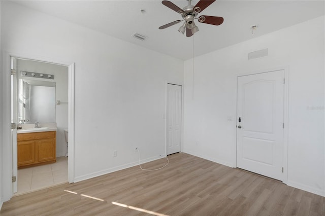 unfurnished bedroom featuring ceiling fan, light wood-type flooring, sink, and connected bathroom