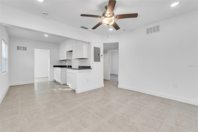 unfurnished living room featuring light tile patterned floors, electric panel, ceiling fan, and sink