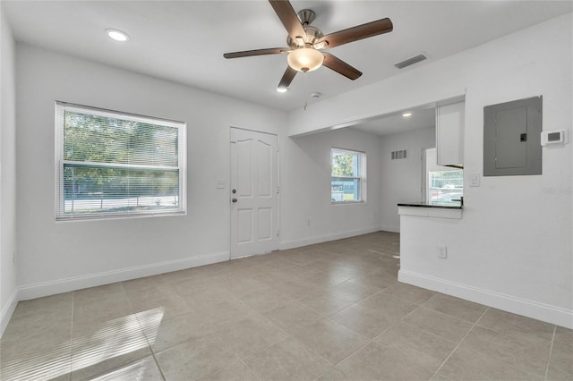 tiled empty room with electric panel and ceiling fan