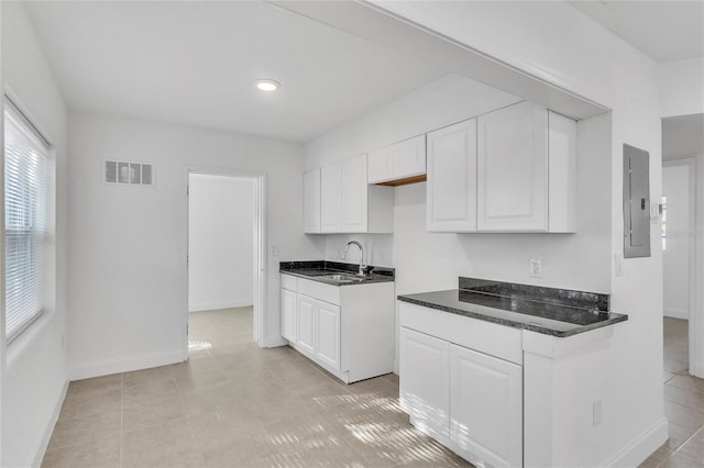 kitchen featuring electric panel, white cabinetry, sink, and light tile patterned flooring