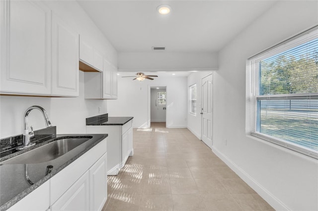 kitchen featuring white cabinets, sink, and dark stone counters