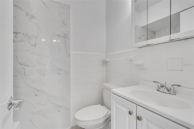 bathroom featuring vanity, toilet, and tile walls