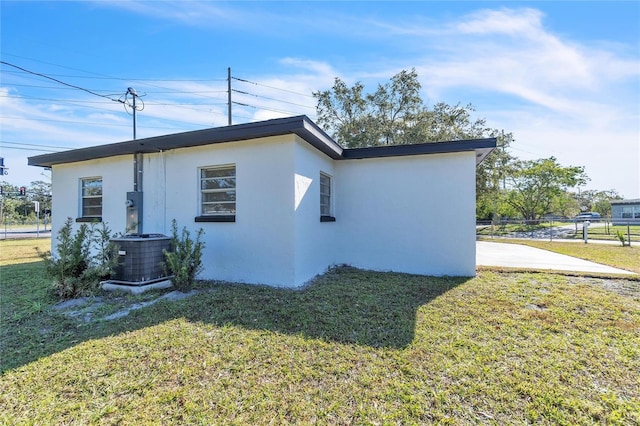 view of side of property featuring a lawn and central air condition unit