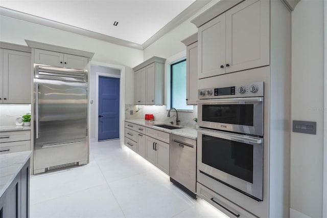 kitchen featuring sink, gray cabinets, light stone countertops, appliances with stainless steel finishes, and tasteful backsplash