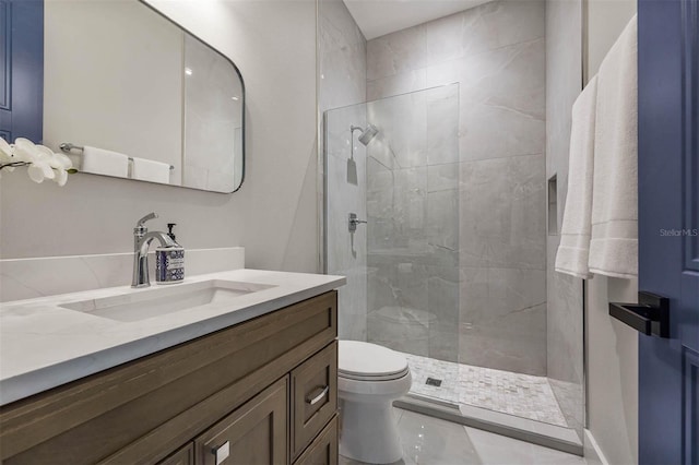 bathroom featuring vanity, a shower with shower door, and toilet